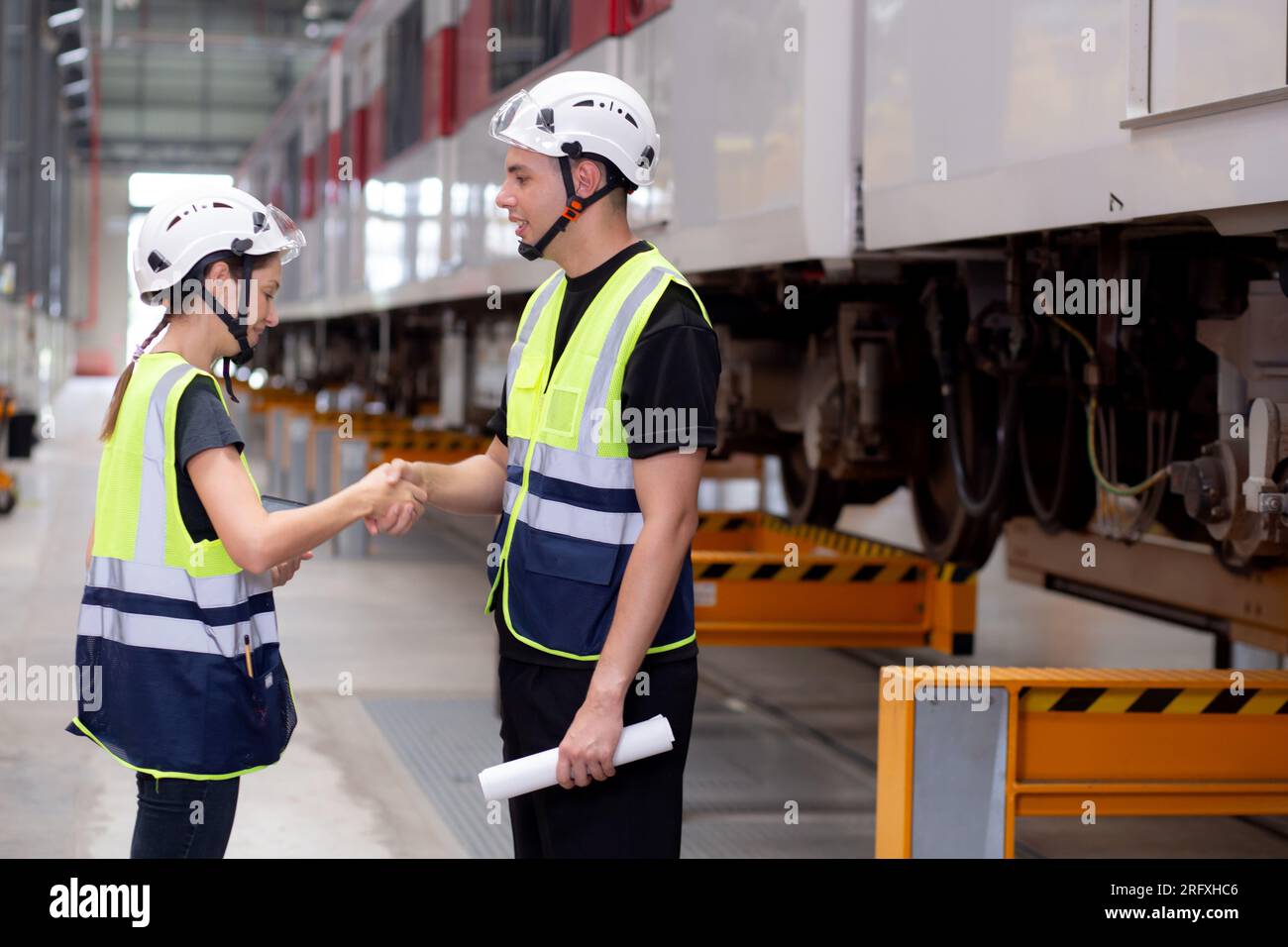 Giovane ingegnere caucasico, uomo e donna, organizzano riunioni di progetto e controllano il treno elettrico per pianificare la manutenzione e la stretta di mano con accordo e de Foto Stock