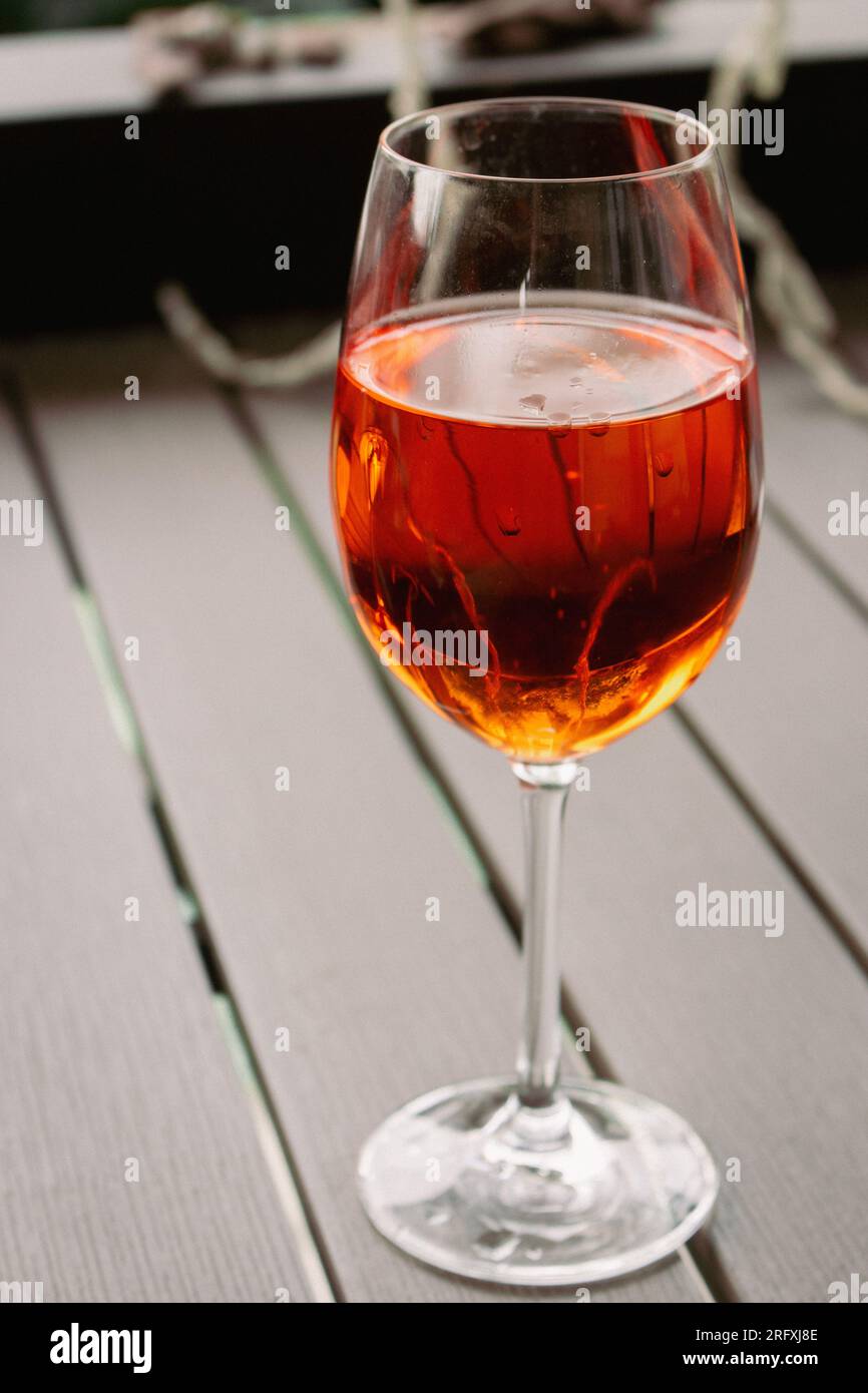 Bicchiere di cocktail Aperol Spritz. Wineglass con vino di rosa. Bar all'aperto. Tavolo del caffè sul marciapiede. Festa con alcol. Cocktail di colore arancione. Foto Stock