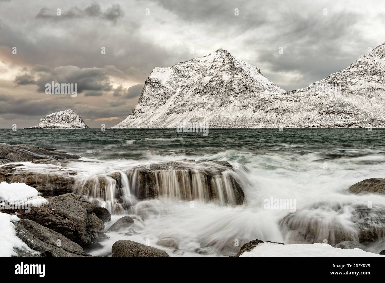 Paesaggio costiero in inverno con movimento dell'acqua, onde che si riversano su grandi pietre Foto Stock