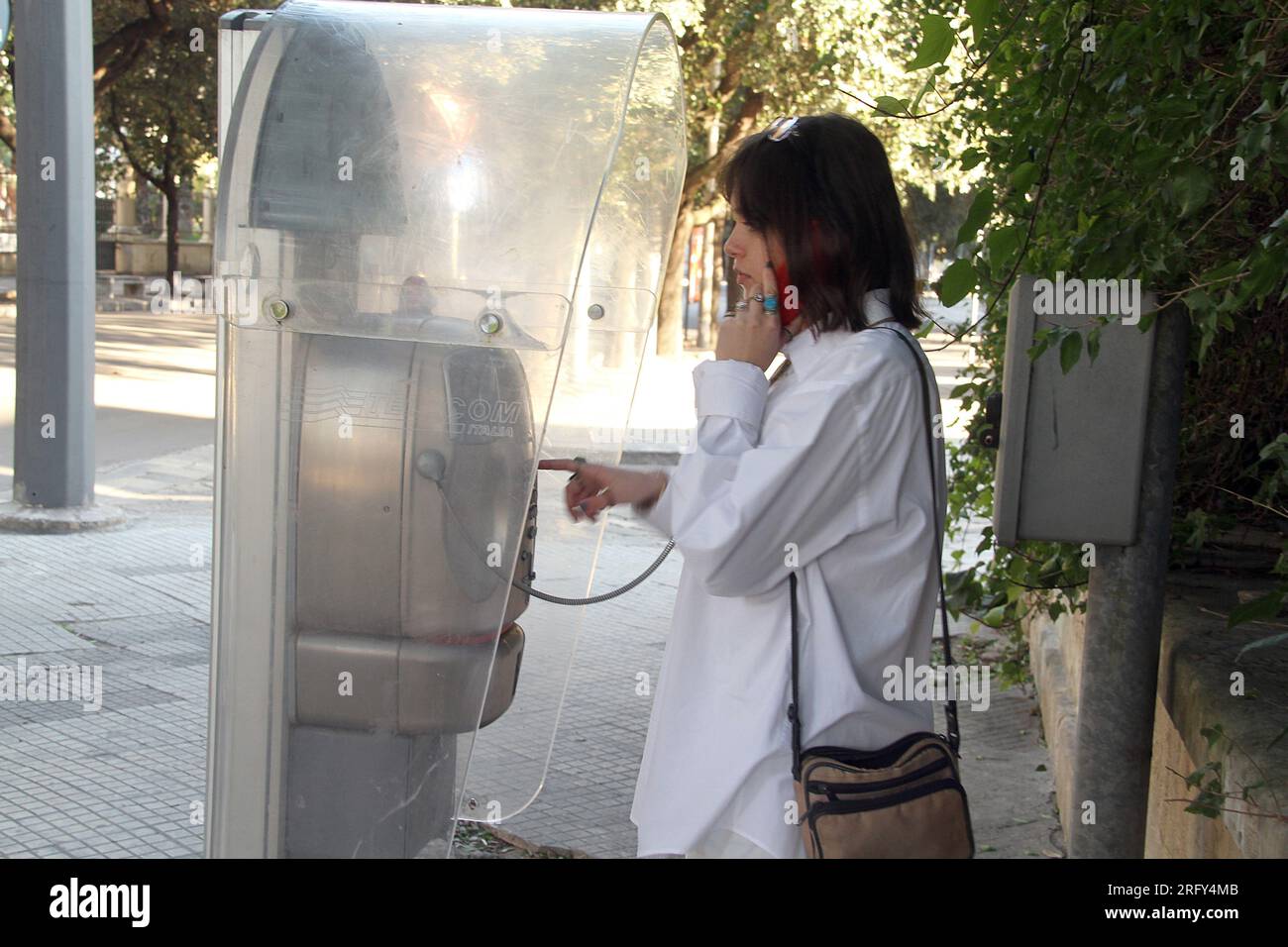 Lecce, Italia. Donna che parla al telefono pubblico. Foto Stock