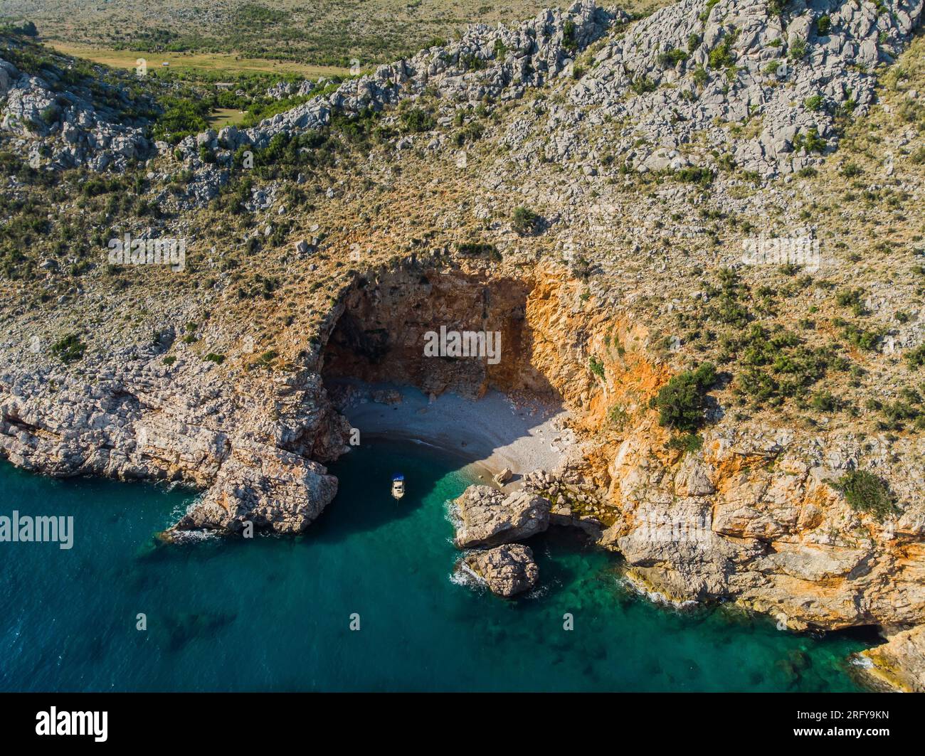 Vista dall'alto di uno splendido porto sul mare. Laguna con acqua blu scuro. Onde vicino alla costa rocciosa e alla barca Foto Stock