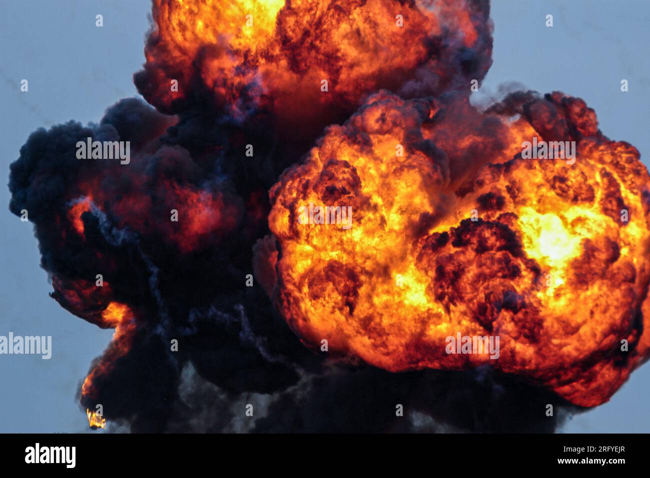 Enorme eruzione di fuoco, esplosione pirotecnica. Fiamme. Fuoco caldo e fumo nero intenso. Esplosione di bombe da uno scenario di attacco al campo di battaglia Foto Stock