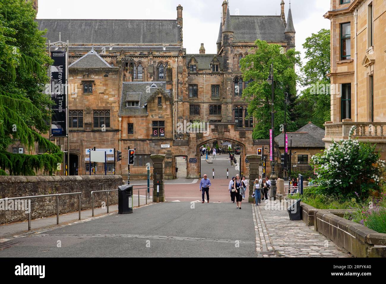 Persone, pedoni, camminando vicino al cancello principale, l'Università di Glasgow, Scozia, Regno Unito. Foto Stock
