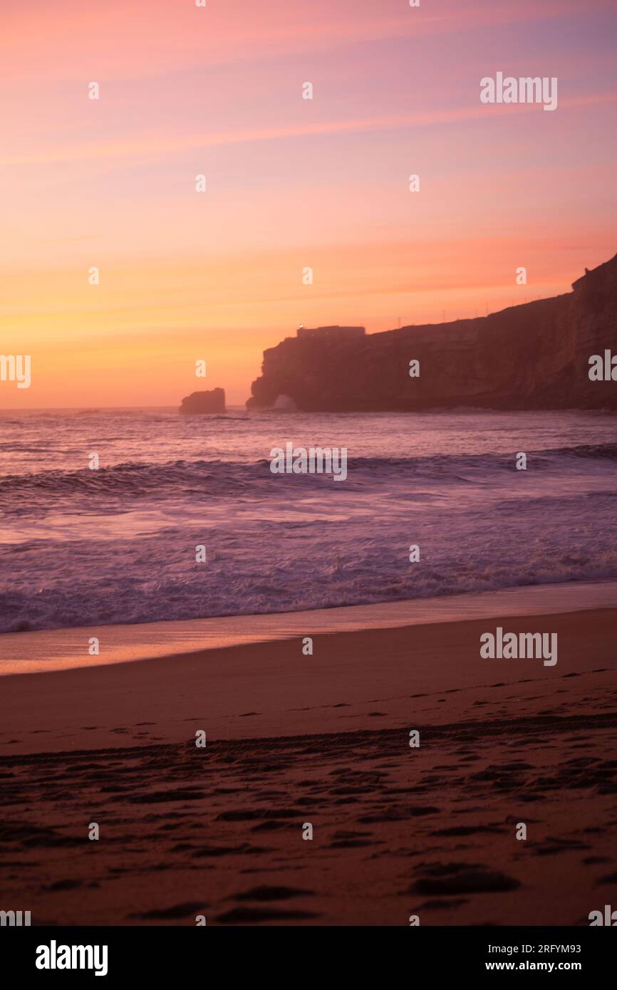 L'affascinante promontorio di Nazaré: L'abbraccio dorato del tramonto dipinge le scogliere, mentre l'oceano sussurra le sue storie senza tempo Foto Stock