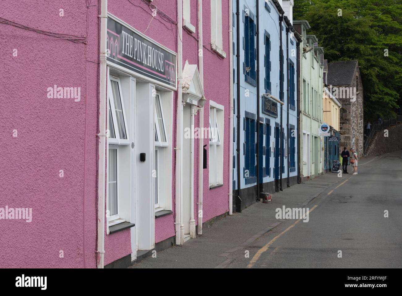 Edifici colorati presso il Porto di Portree sull'Isola di Skye, con i turisti all'estremità di Quay Street che prenotano un Tour del Mare Foto Stock