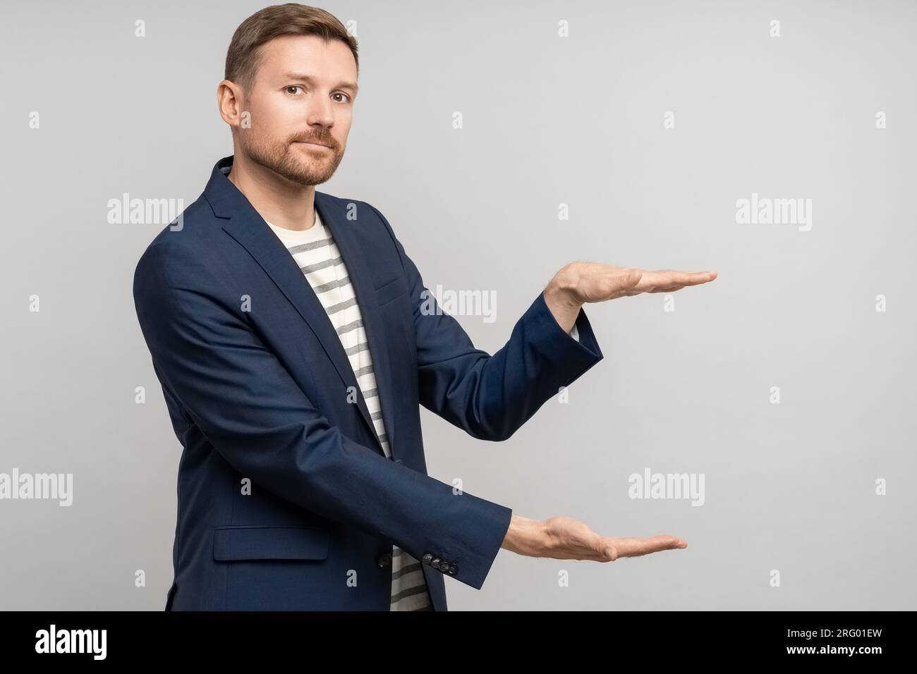 Uomo interessato promoter in abiti da lavoro mostra con le mani taglie di sconto in vendita sul muro dello studio Foto Stock