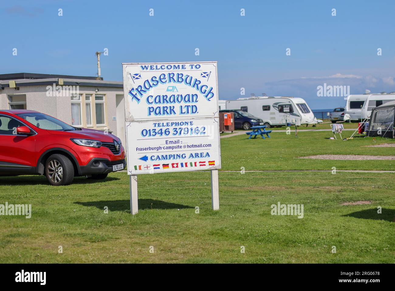Un cartello in legno dipinto a mano per Fraserburgh Caravan Park. Potete vedere carovane, cielo blu e mare sullo sfondo. Si tratta di un luogo turistico vicino alla spiaggia Foto Stock