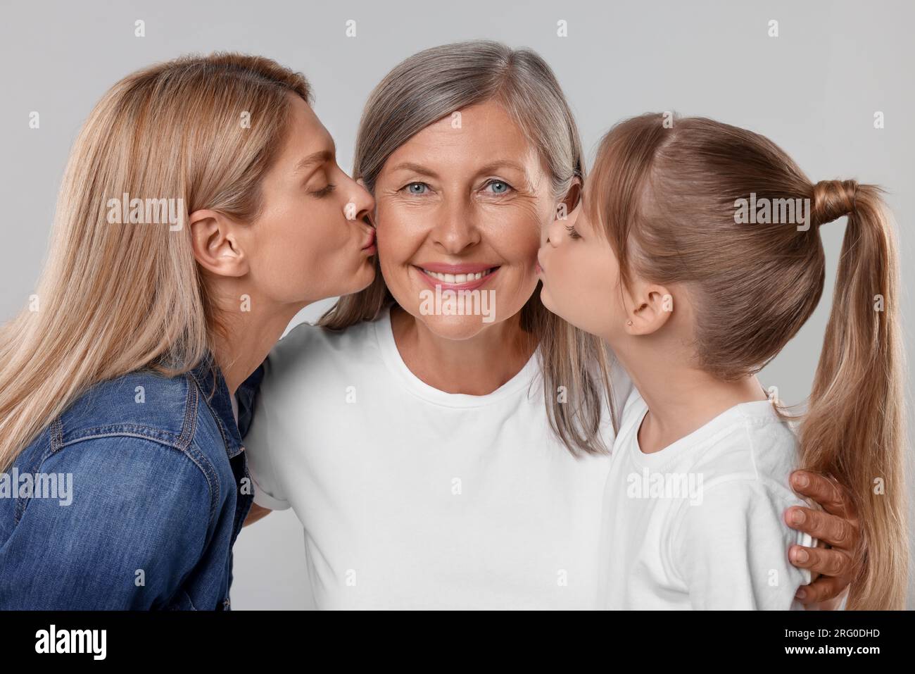 Tre generazioni. Nonna felice, sua figlia e sua nipote su sfondo grigio chiaro Foto Stock