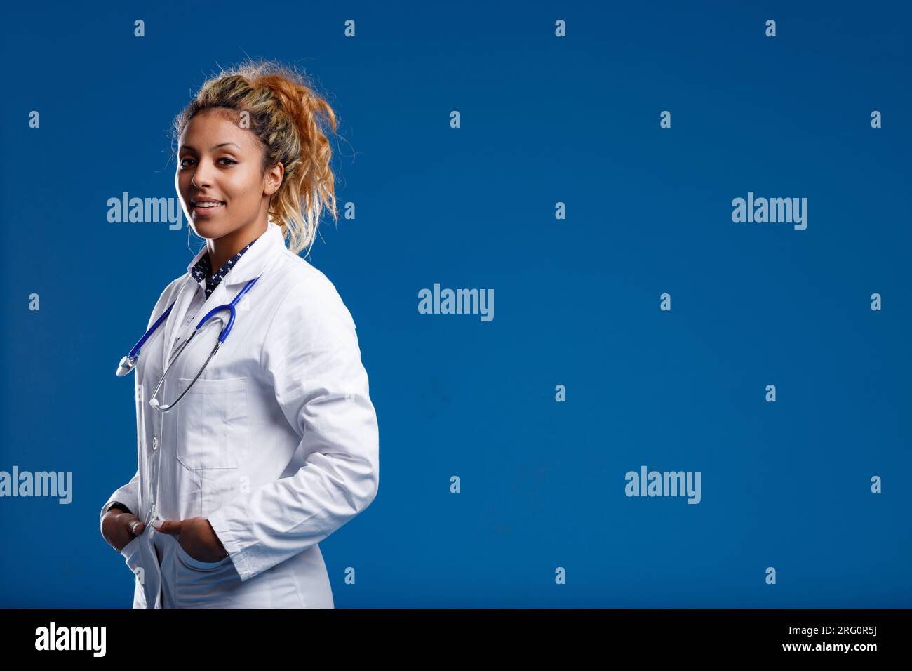 Medico esperto, che si occupa di biologia e cura umana. Giovane donna dalla pelle marrone in camice bianco, non dimentica che i pazienti sono persone, non solo corpi Foto Stock