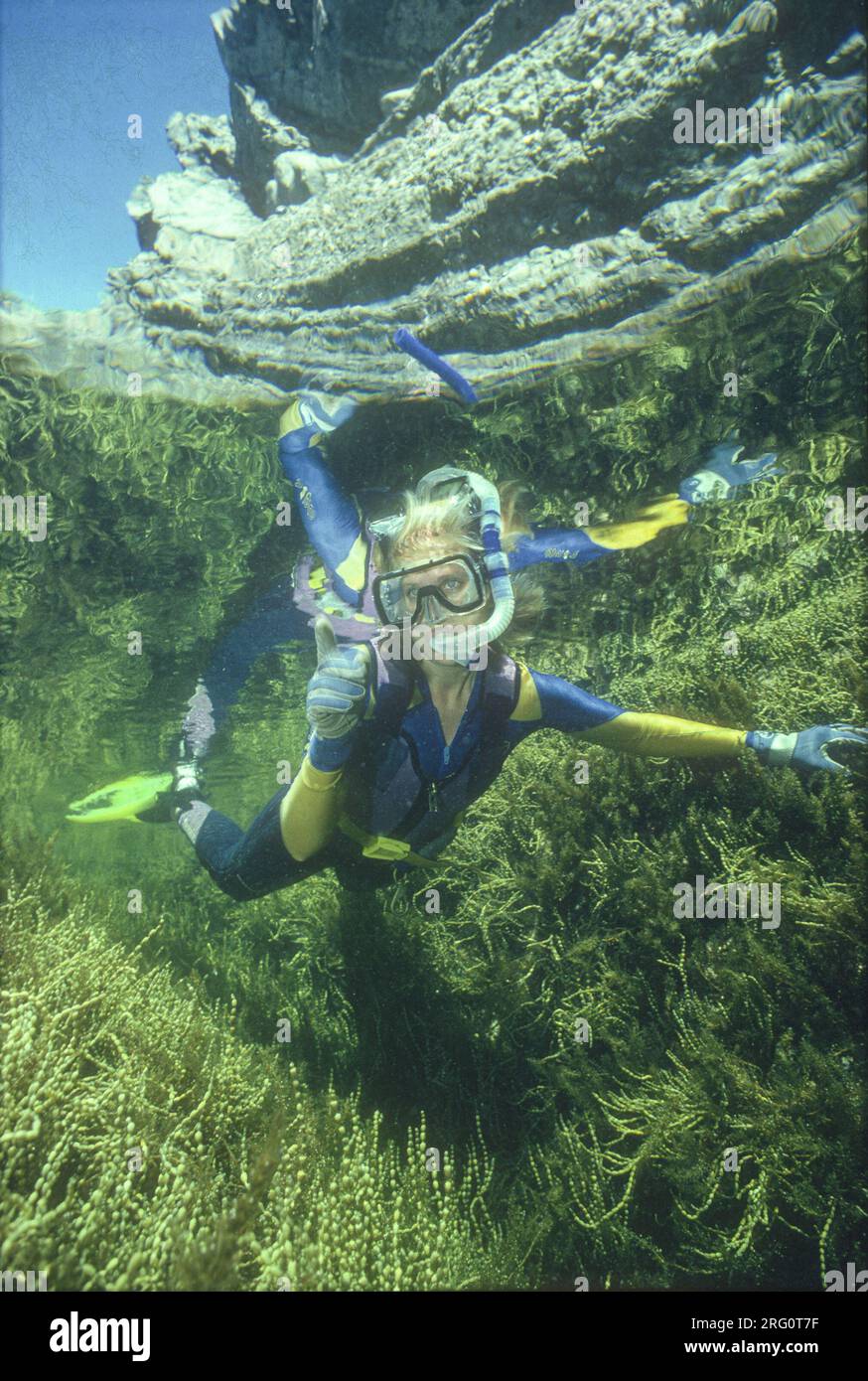 Una donna che fa snorkeling esplorando la profonda piscina di roccia fiancheggiata da alghe. Status Rock, Seal Rocks, New South Wales, Australia Foto Stock