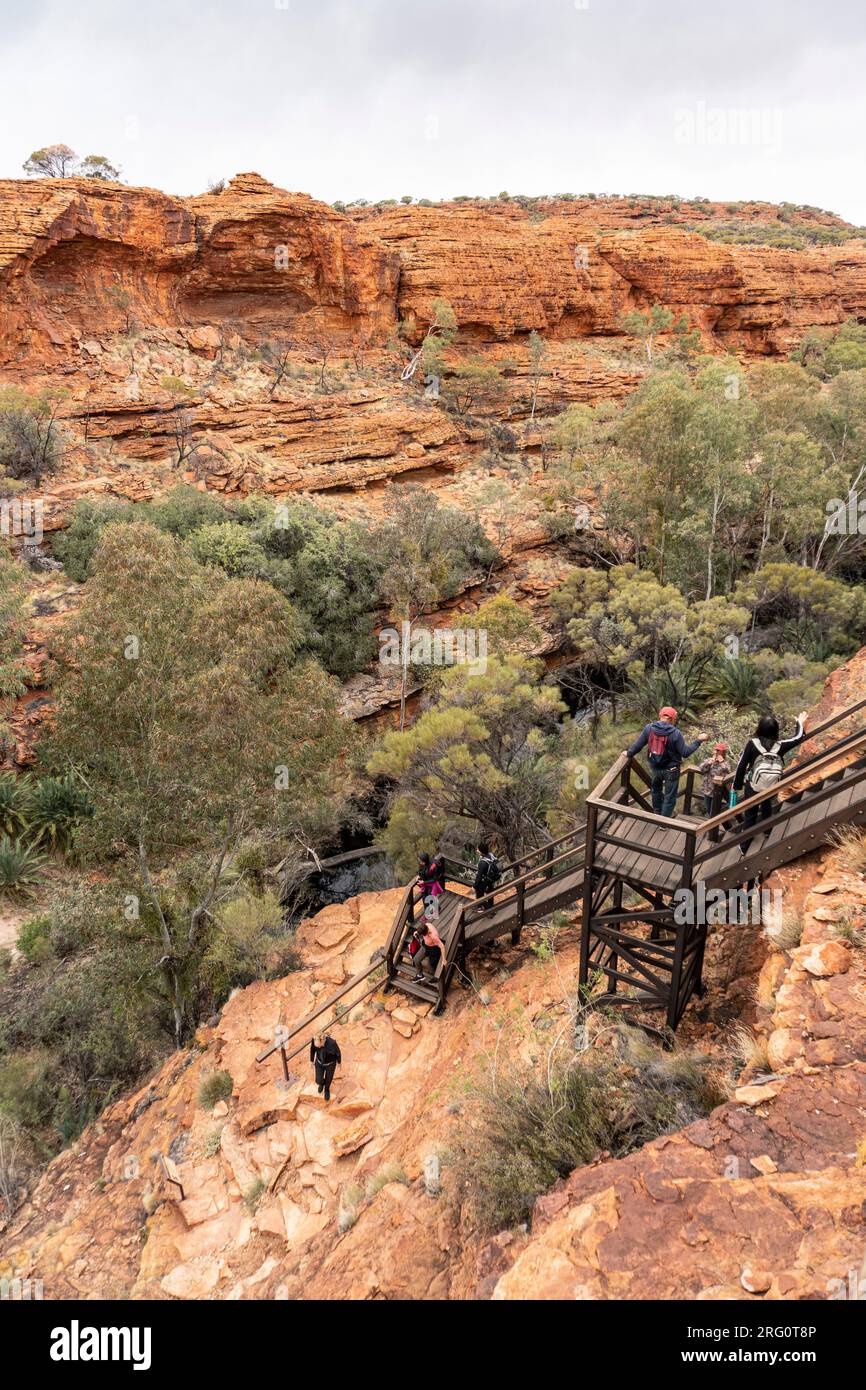 Gli escursionisti scendono a piedi nel braccio nord del Kings Canyon con Kings Creek alla base. Parco nazionale di Watarrka, territorio del Nord, Australia Foto Stock