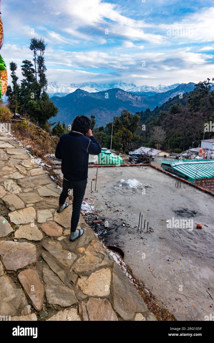 14 ottobre 2022, Uttarakhand India. Turista sorseggiando un tè, ammirando l'Himalaya innevato a Garhwal, Uttarakhand, India. Tranquilla vista sulle montagne Foto Stock