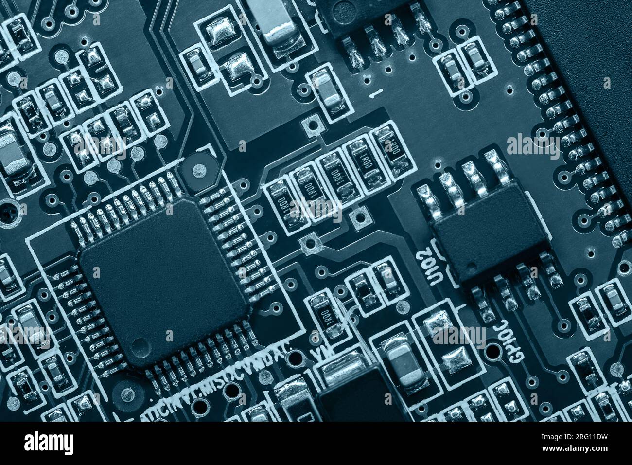 Primo piano della scheda a circuito stampato con processore, circuiti integrati e molti altri componenti elettrici passivi a montaggio superficiale. Foto Stock