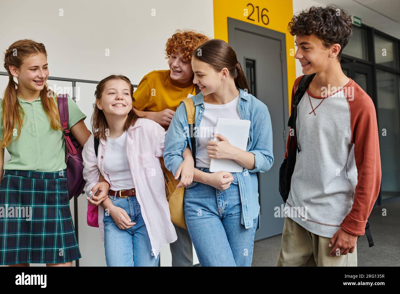 ritorno a scuola, allegri compagni di classe che sorridono nel corridoio scolastico, vita studentesca, amici che si divertono Foto Stock