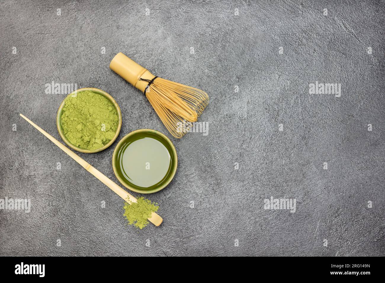 Tè Matcha in una ciotola. Tè Matcha verde in polvere in una ciotola di legno. Frusta di bambù e cucchiaio sul tavolo. Copia spazio. Spianatura piatta. Sfondo nero Foto Stock