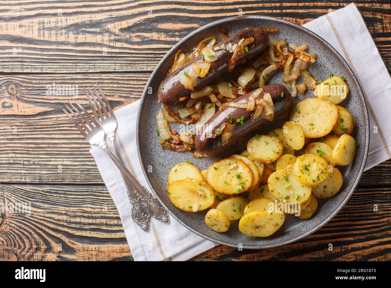 Tradizionale budino nero caldo con cipolle fritte e patate da vicino su un piatto sul tavolo. Vista superiore orizzontale dall'alto Foto Stock