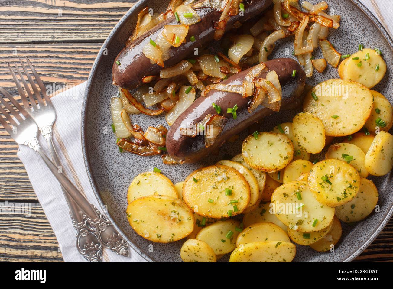 Budino nero fatto in casa con cipolle fritte con contorno di patate da vicino su un piatto sul tavolo. Vista superiore orizzontale dall'alto Foto Stock