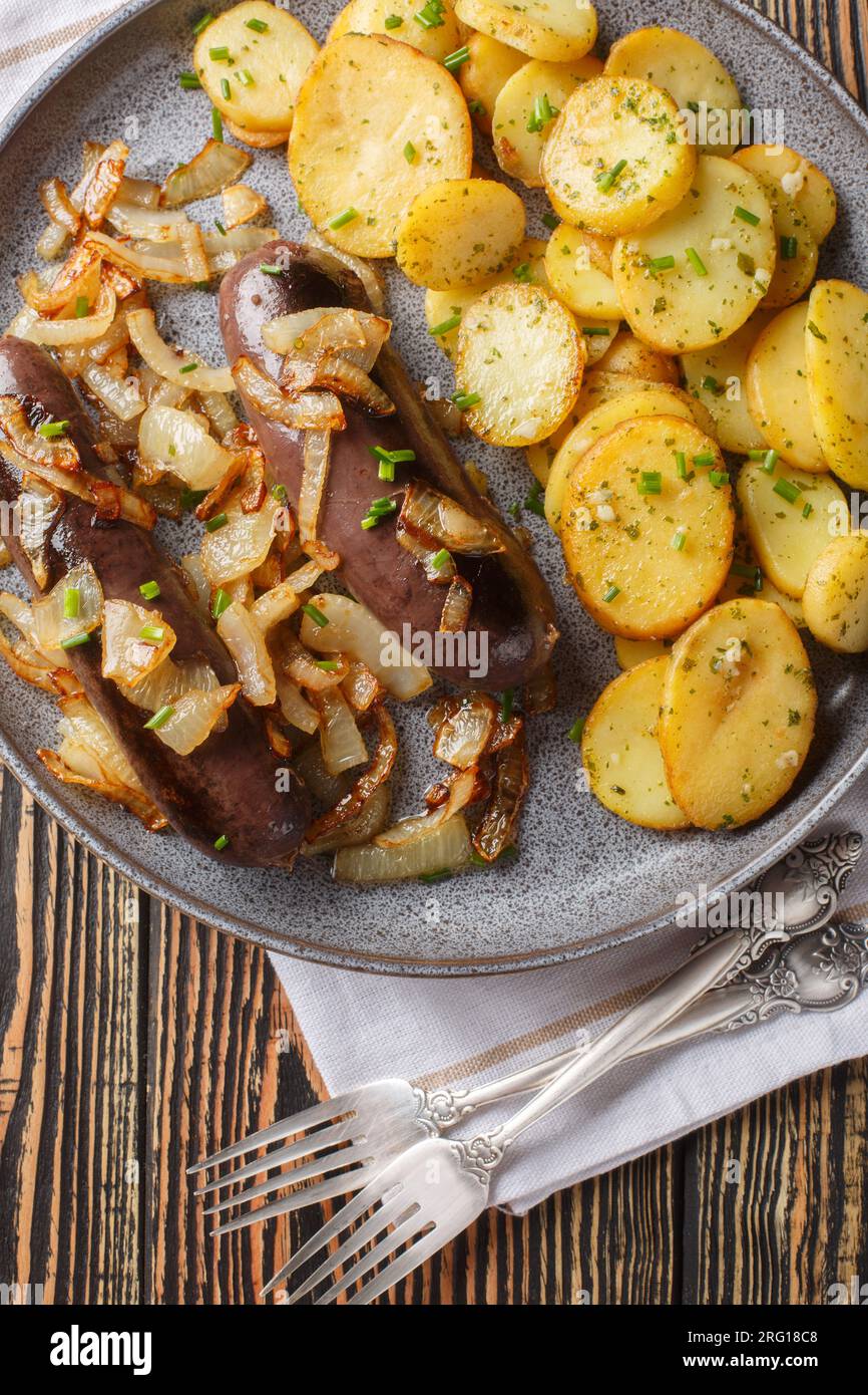 Salsiccia rustica e gustosa fritta con primo piano di patate sul piatto sul tavolo. Vista dall'alto verticale Foto Stock