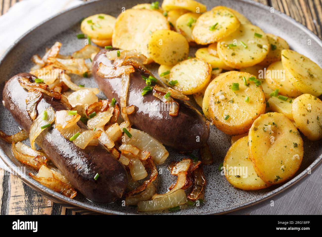 Budino nero fatto in casa con cipolle fritte con contorno di patate da vicino su un piatto sul tavolo. Orizzontale Foto Stock