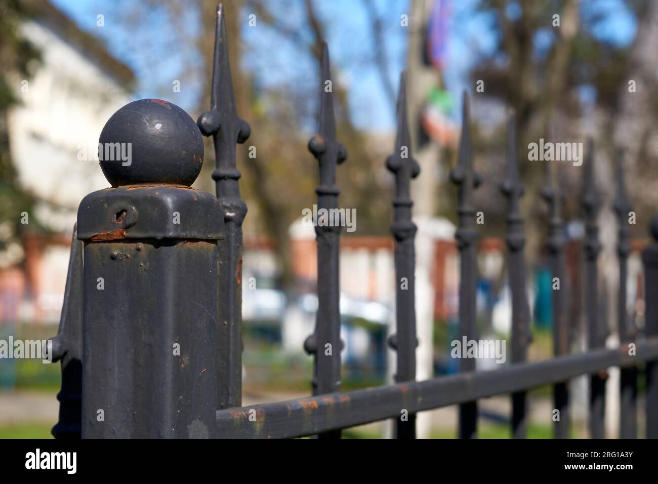 Recinzione nera in metallo con barre a punta a forma di lancia su una vera strada Foto Stock