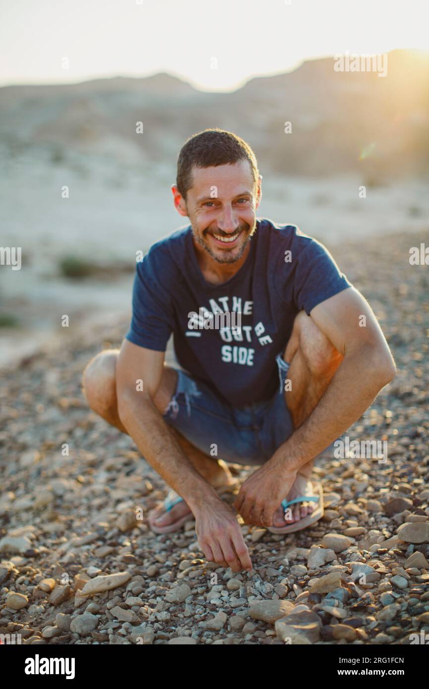Un giovane che sorride nel deserto al tramonto Foto Stock