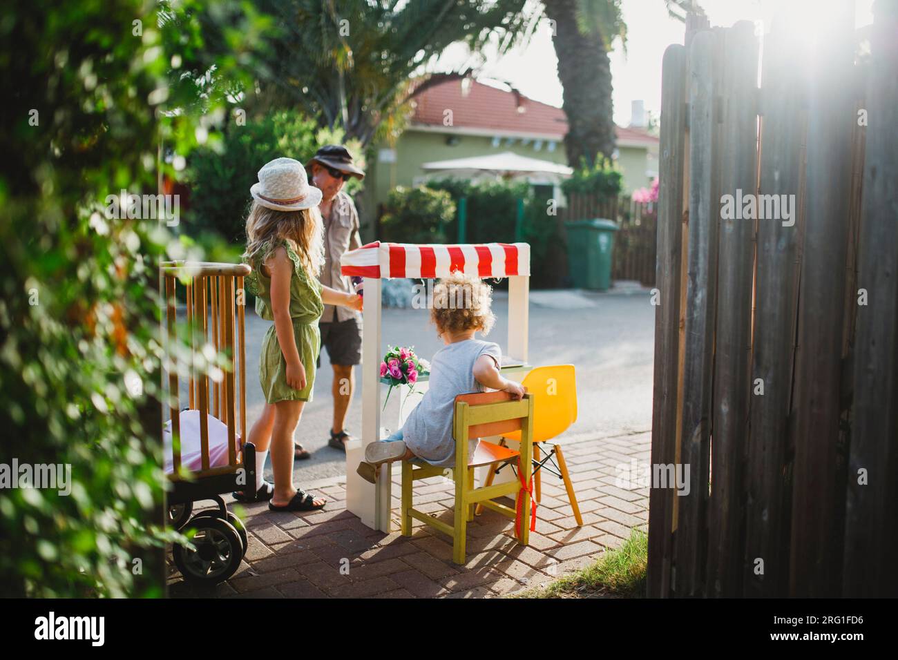 Due sorelle che giocano con il mercato vendono fiori a un uomo Foto Stock