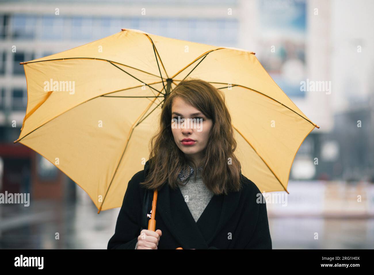Ritratto di una giovane donna che tiene un ombrello giallo Foto Stock