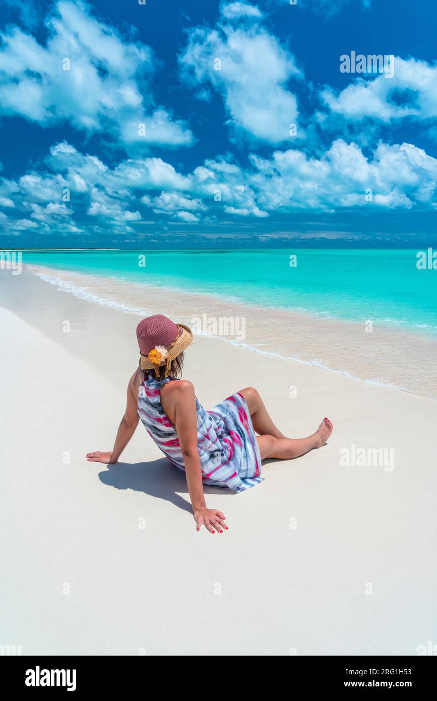 Ritratto di donna con cappello seduto sulla spiaggia di sabbia rosa, Mar dei Caraibi Foto Stock