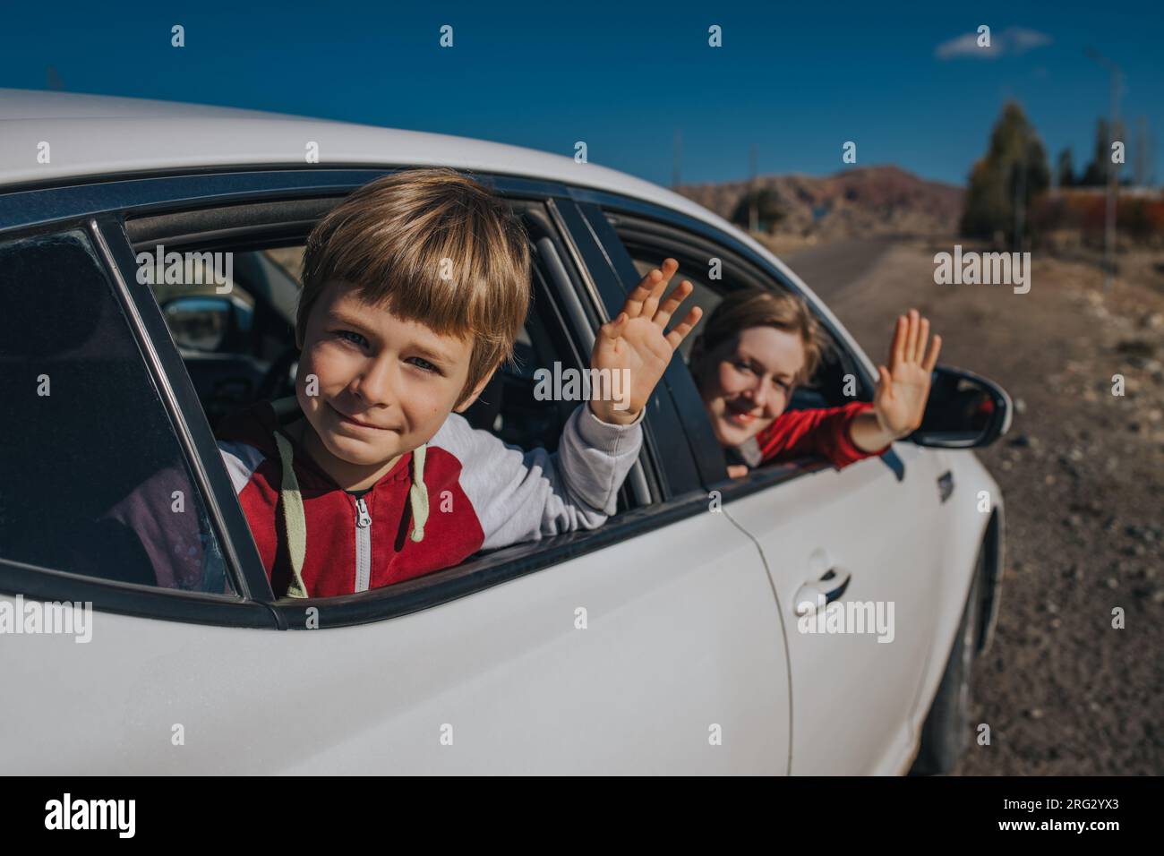 Madre e figlio felici che agitavano le mani dal finestrino dell'auto Foto Stock