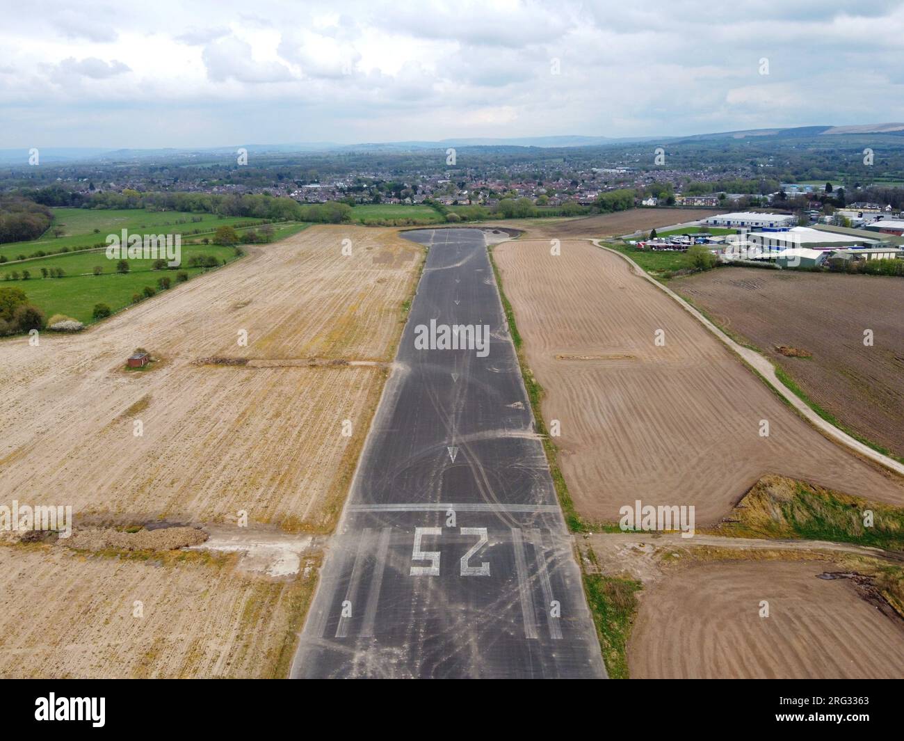 Veduta aerea aerea della restante sezione della pista 25 dell'aerodromo di Woodford, Regno Unito con edifici industriali e la città di Poynton in Foto Stock