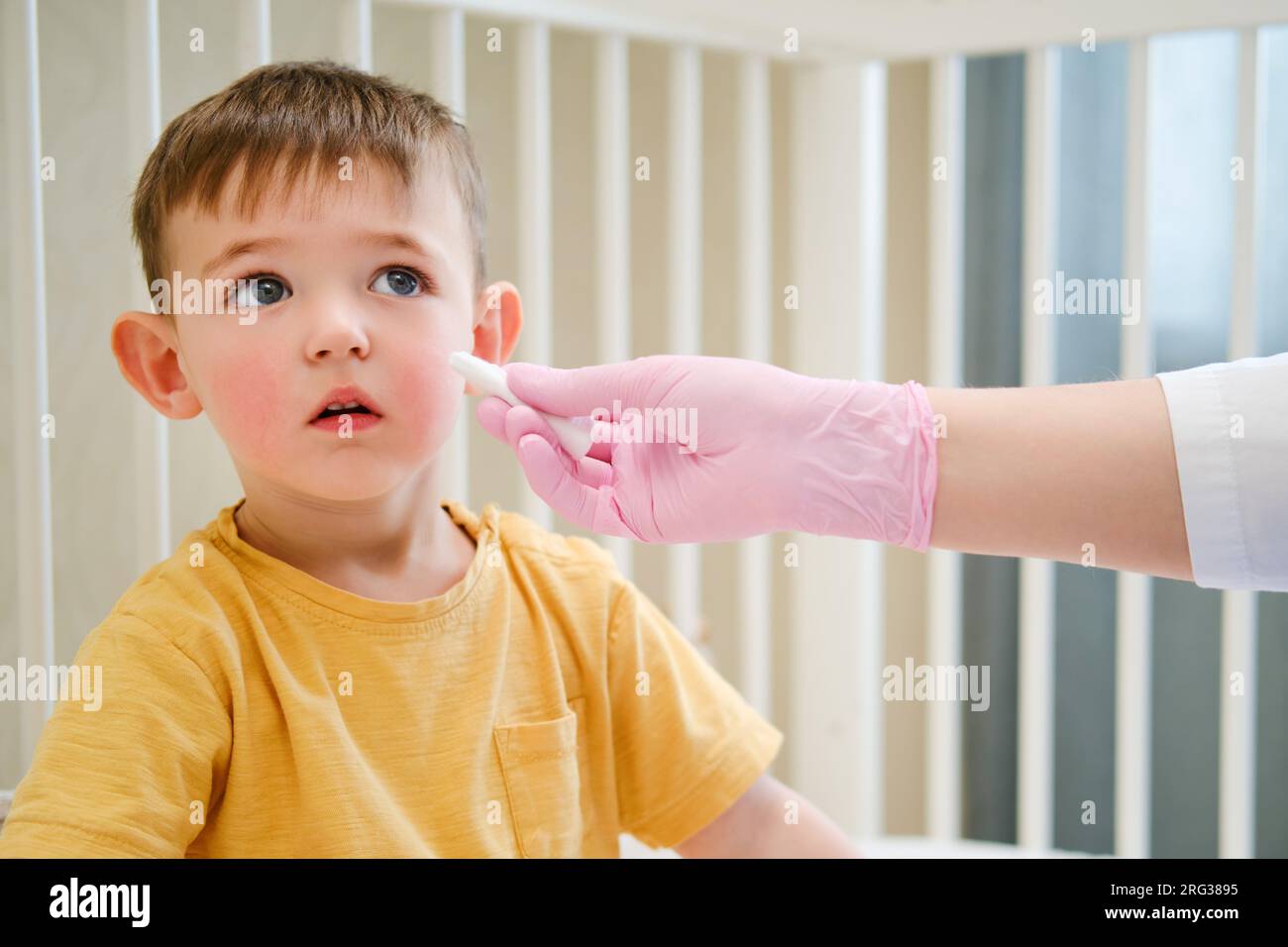 Durante l'esame medico, il pediatra ha usato un tampone di cotone per pulire delicatamente il naso del bambino. Bambino di circa due anni (un anno e undici mesi) Foto Stock