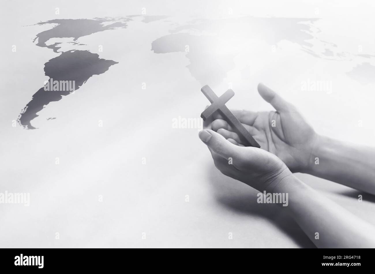 Cristiano che tiene in mano la Santa Croce di Gesù Cristo e prega per le missioni mondiali, l'evangelismo e la mappa del mondo Foto Stock