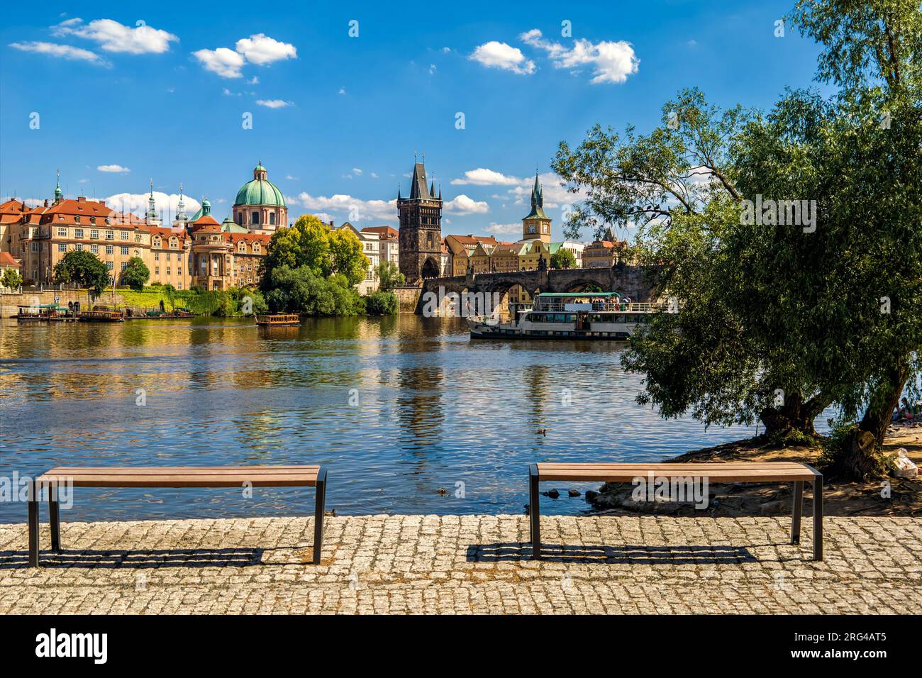 Due panchine e il famoso Ponte Carlo sul fiume Moldava sotto il cielo blu a Praga, Repubblica Ceca. Foto Stock