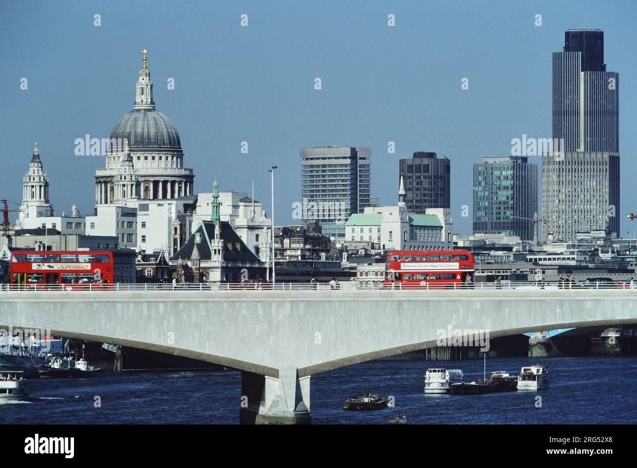 Autobus rossi sul ponte Waterloo con lo skyline della città e la Cattedrale di St Paul alle spalle. Londra, Inghilterra. Circa 1985 Foto Stock