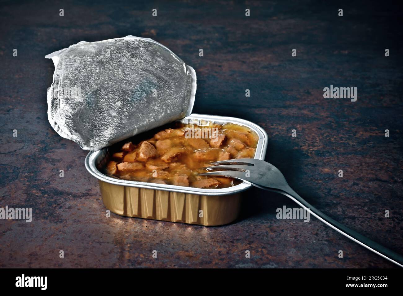 Aprire la confezione di alimenti umidi per animali domestici con la forchetta sul tavolo. Foto Stock