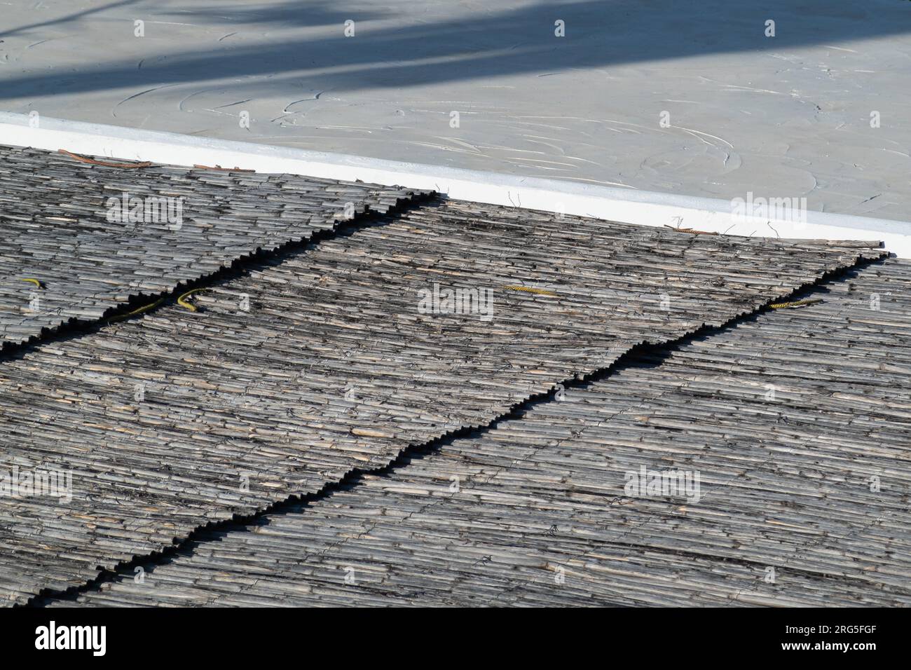 Motivo a linee incrociate in cemento bianco a contrasto hjigih e tetto in paglia Foto Stock
