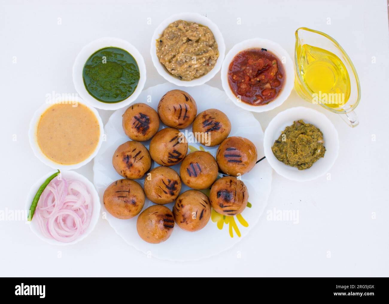 Litti in piatto bianco con pomodoro, brinjal, patate, gaurd appuntito e chutney di coriandolo o chokha e ghee. È popolare in Bihar, Uttar Pradesh Foto Stock