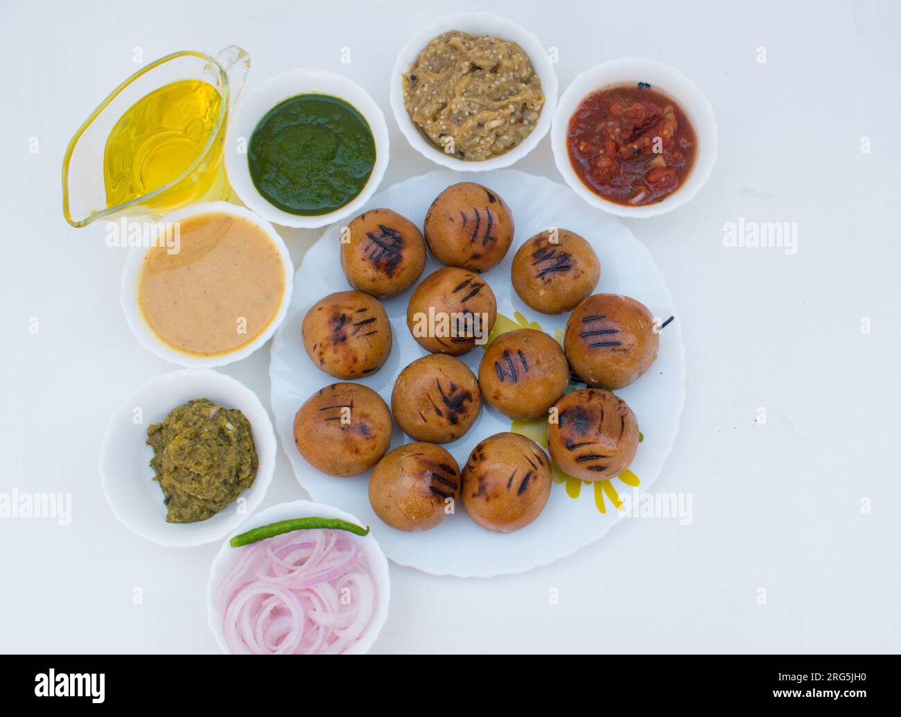 Litti in piatto bianco con pomodoro, brinjal, patate, gaurd appuntito e chutney di coriandolo o chokha e ghee. È popolare in Bihar, Uttar Pradesh Foto Stock