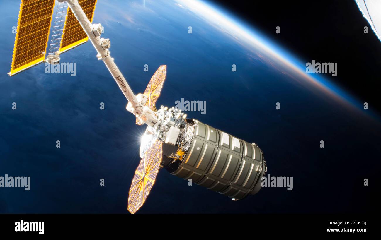 La navicella spaziale Cygnus nelle impugnature del braccio robotico Canadarm2 sopra la Terra. Foto Stock