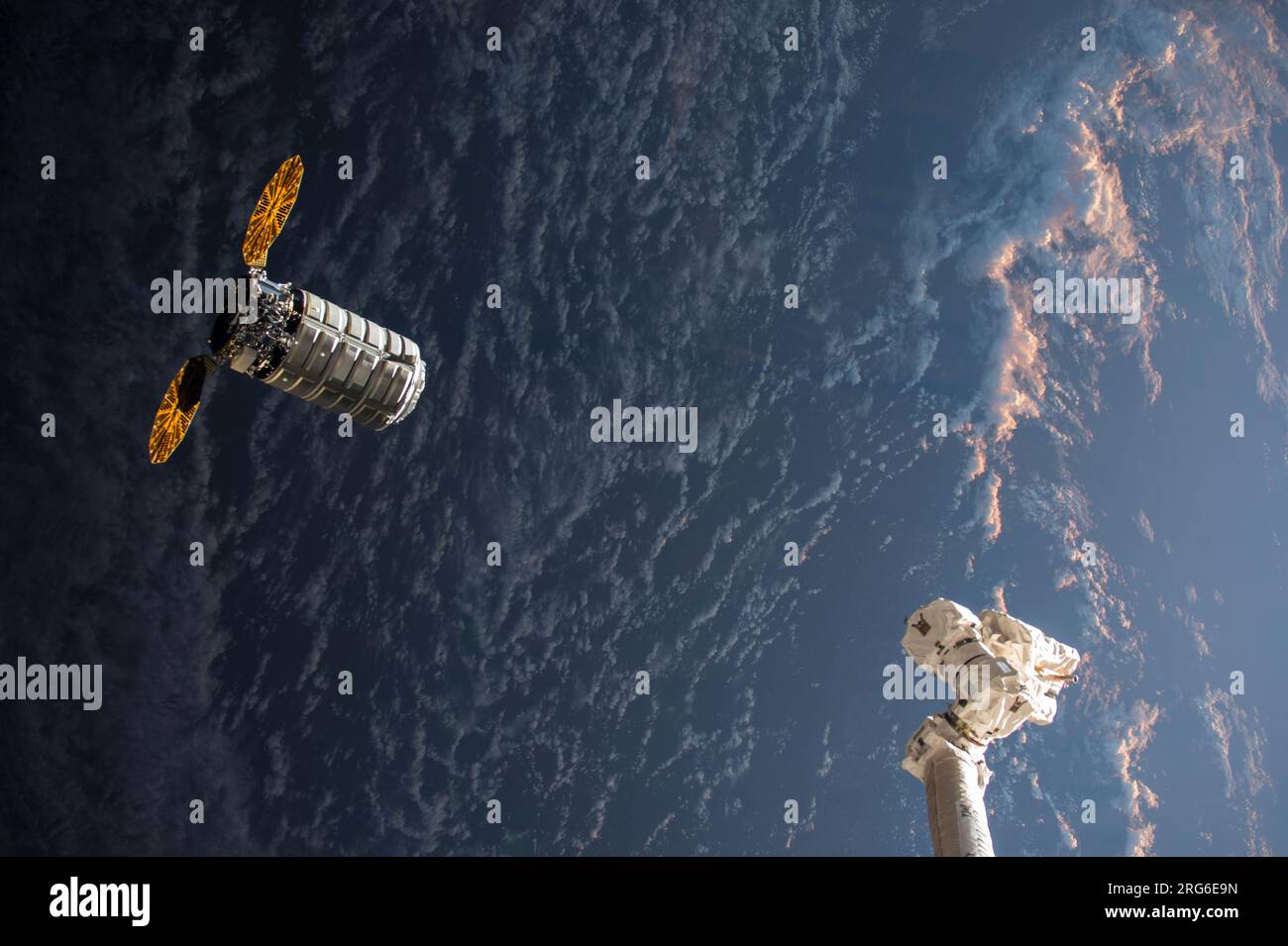 Il veicolo spaziale Cygnus si avvicina al braccio robotico Canadarm2 mentre vola verso un'alba orbitale. Foto Stock