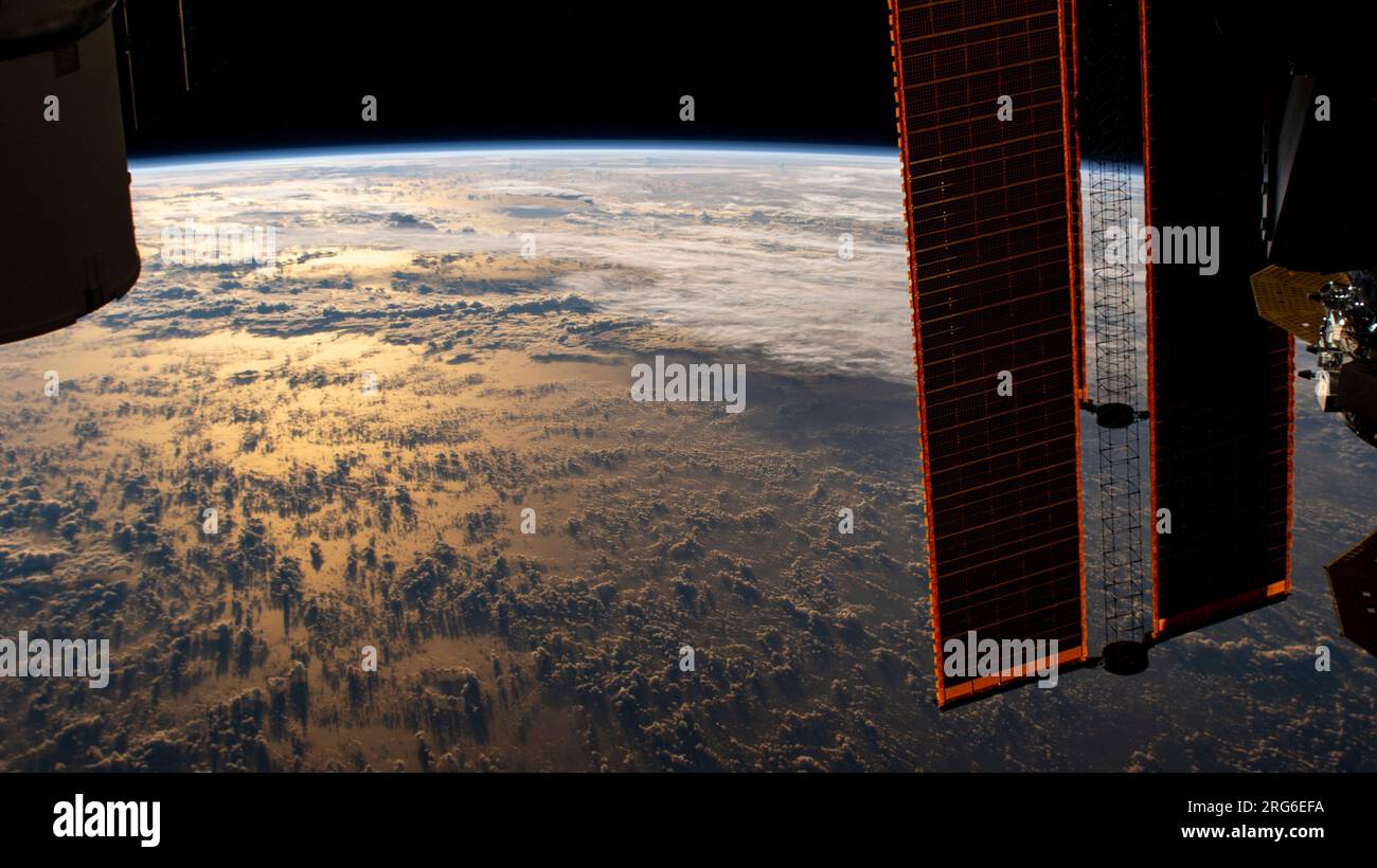 La stazione spaziale Internazionale orbita sopra la Terra sotto forma di raggi di sunglint sul Mare delle Filippine durante un'alba orbitale. Foto Stock