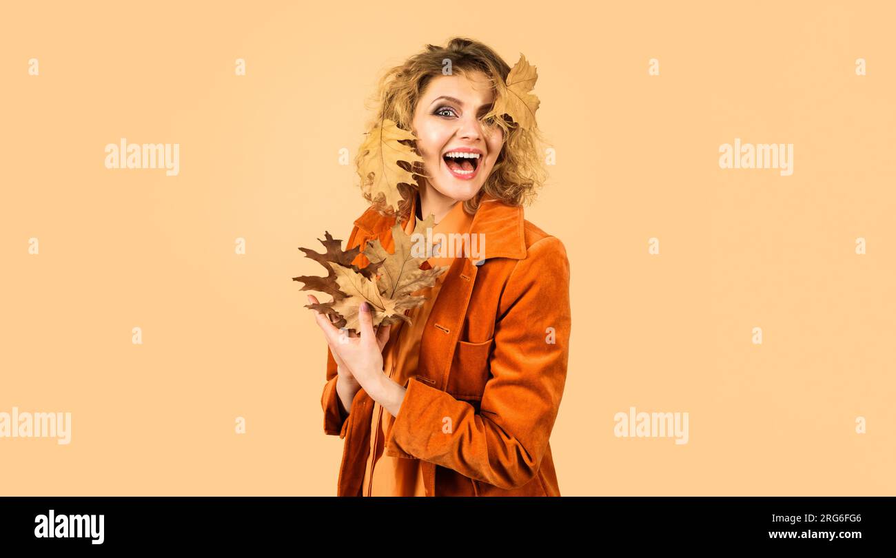 Ragazza felice in abiti alla moda con foglie autunnali. Modello femminile autunnale in camice arancione con foglie autunnali. Abbigliamento autunnale per donne. Bella donna Foto Stock