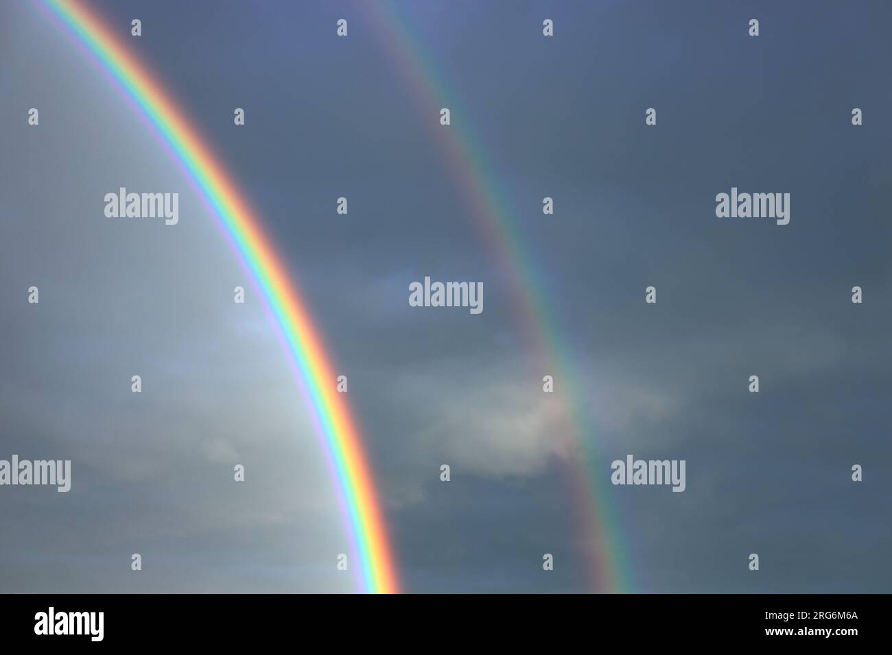 Magico doppio arcobaleno sullo sfondo del cielo blu subito dopo la pioggia durante il tramonto Foto Stock
