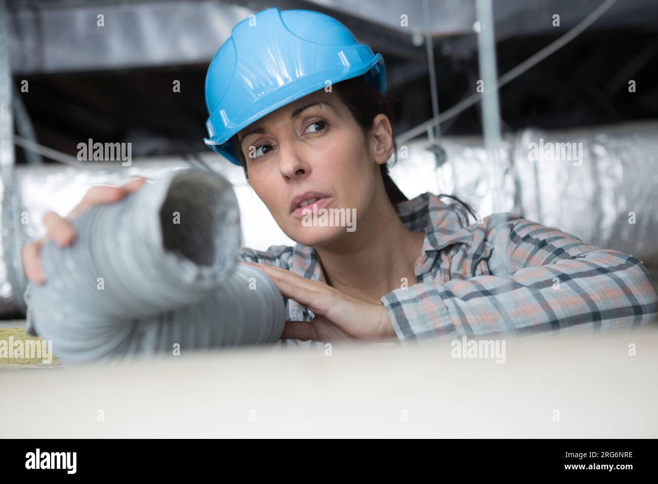 elettricista femmina che tiene il tubo di protezione flessibile Foto Stock