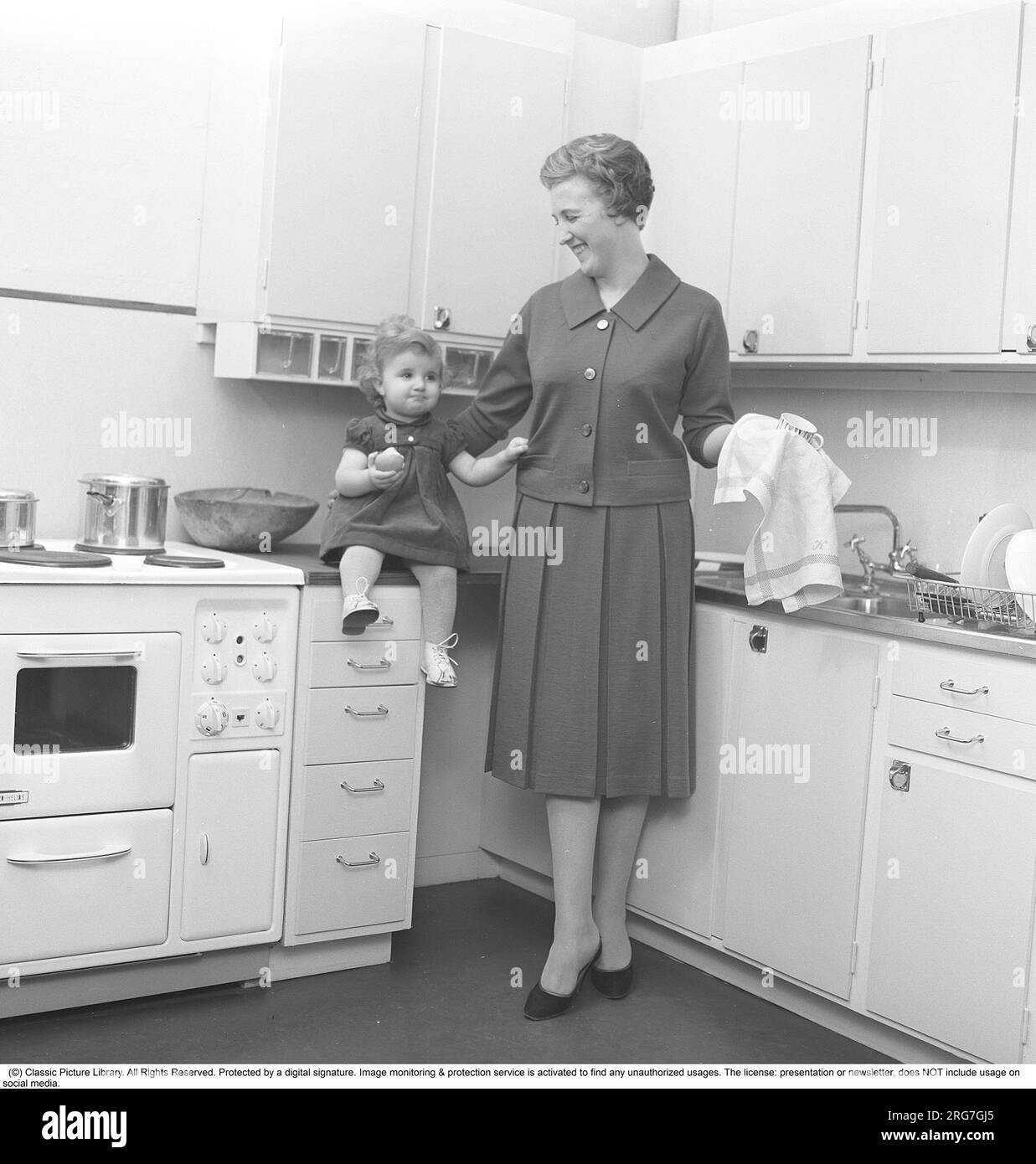 Cucina negli anni '1950 Una donna è vista nella cucina degli anni '1950 con sua figlia che fa i piatti. Svezia 1958. Kristoffersson rif CC65-7 Foto Stock