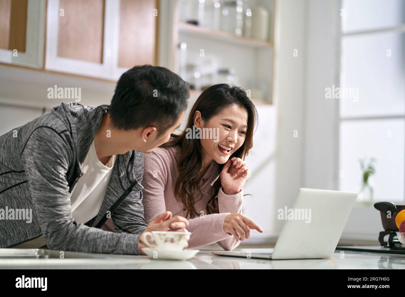 giovane coppia asiatica che utilizza il computer portatile insieme in famiglia cucina a casa Foto Stock