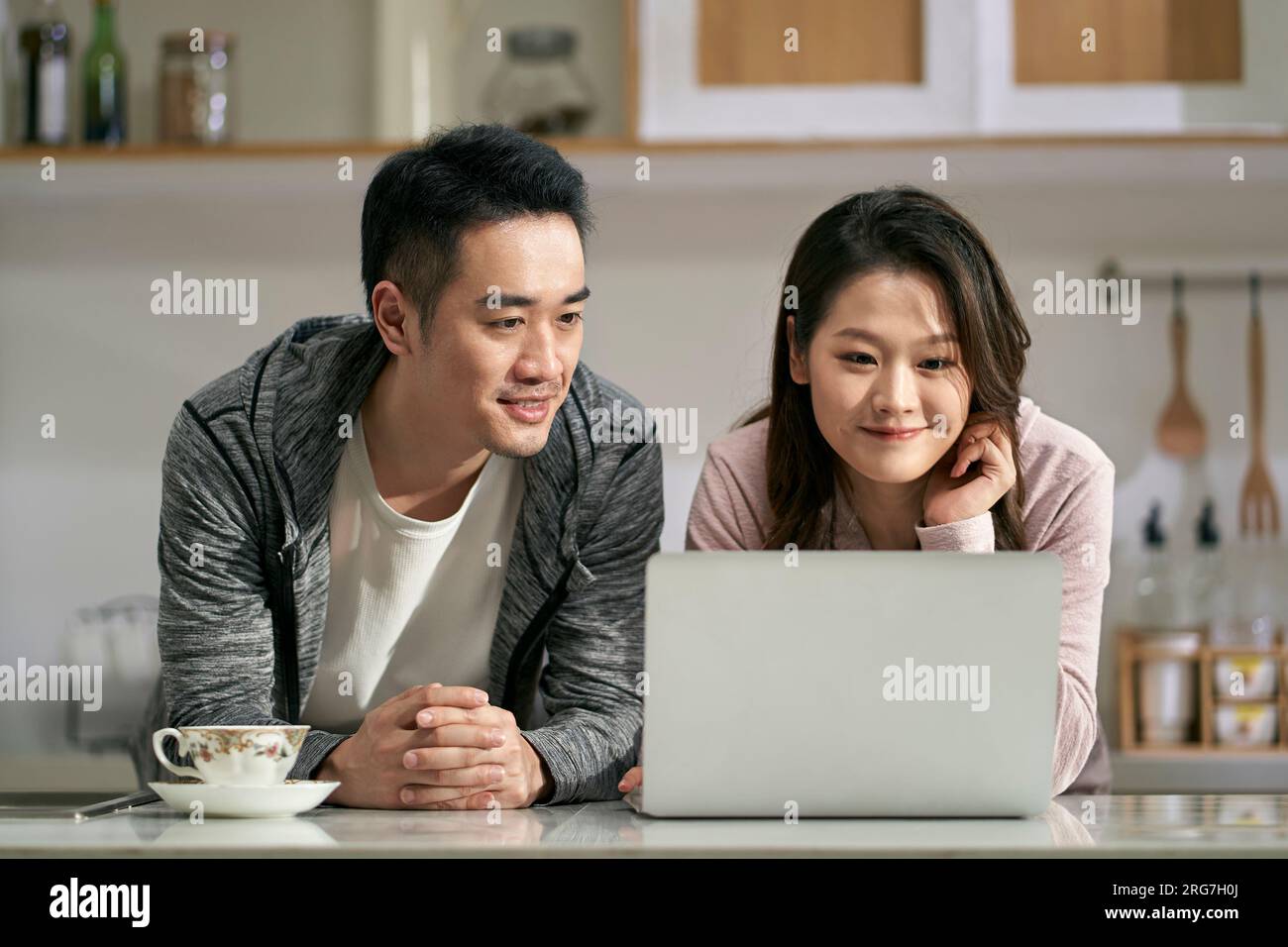 giovane coppia asiatica che utilizza il computer portatile insieme in famiglia cucina a casa Foto Stock