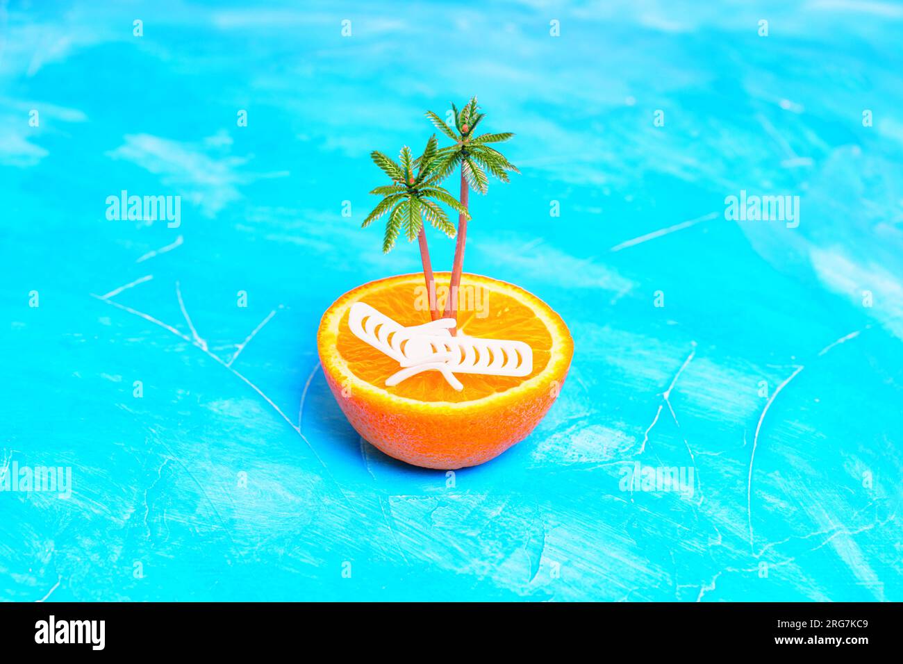 Composizione isolana tropicale composta da una metà arancione fresca con una poltrona giocattolo e palme in cima. Paradiso tropicale creativo e promozioni per le vacanze Foto Stock