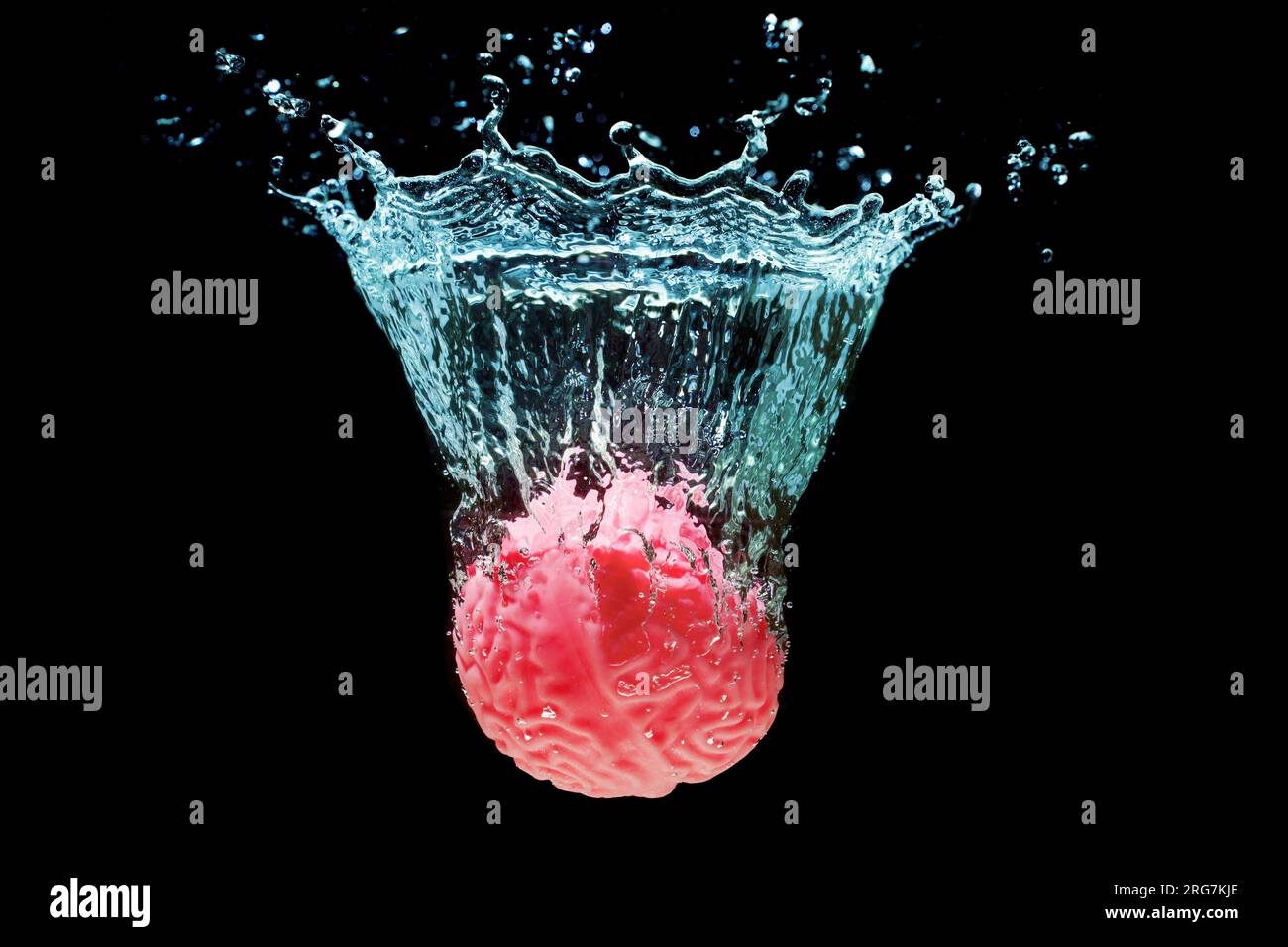 Replica anatomica rosa di un cervello umano immerso nell'acqua con schizzi isolati su nero. Viaggio profondo di scoperta ed esplorazione di sé stessi. Foto Stock