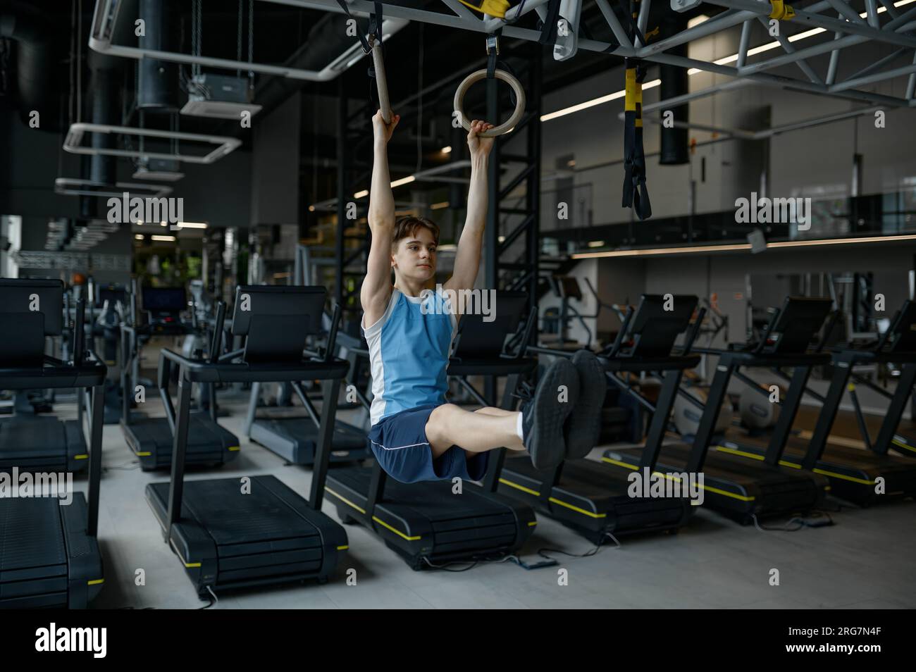 Un teenager forte che si macchia sul ring di ginnastica nella palestra moderna Foto Stock Un teenager forte che si macchia sul ring di ginnastica nella palestra moderna Foto Stock